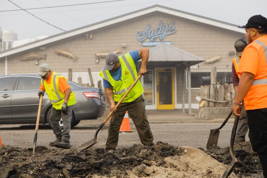 Crew shoveling out damaged asphalt for a patch repair