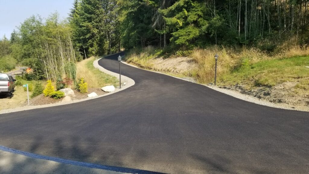 Freshly paved asphalt driveway curving through a wooded lot