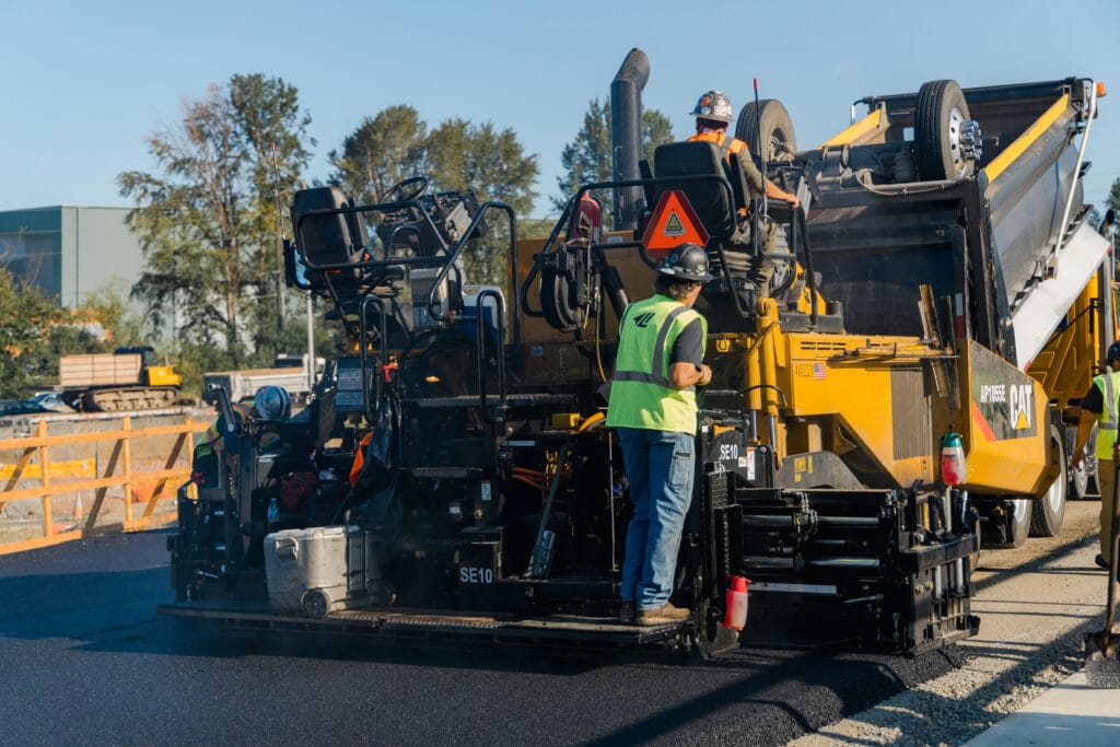 Paving crew running an asphalt paver on a road job